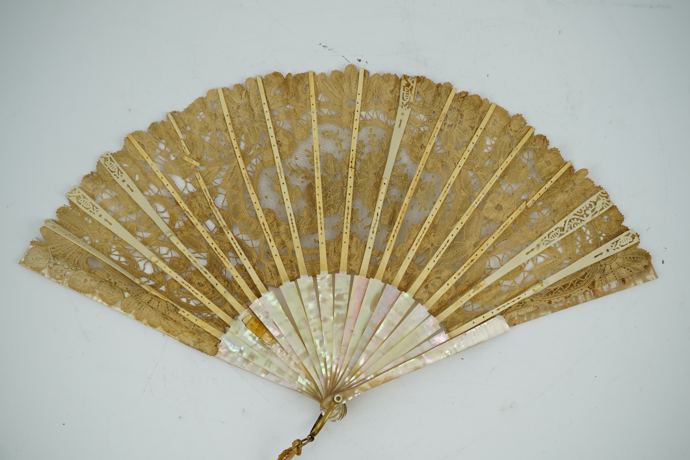 Three novelty fans with a mixed Brussels lace fan and black lace fan, a small language of love in flowers fan, a paper windmill advertising French Café fan, a carved cream Bakelite fan, a black and gilt, lace and sequin